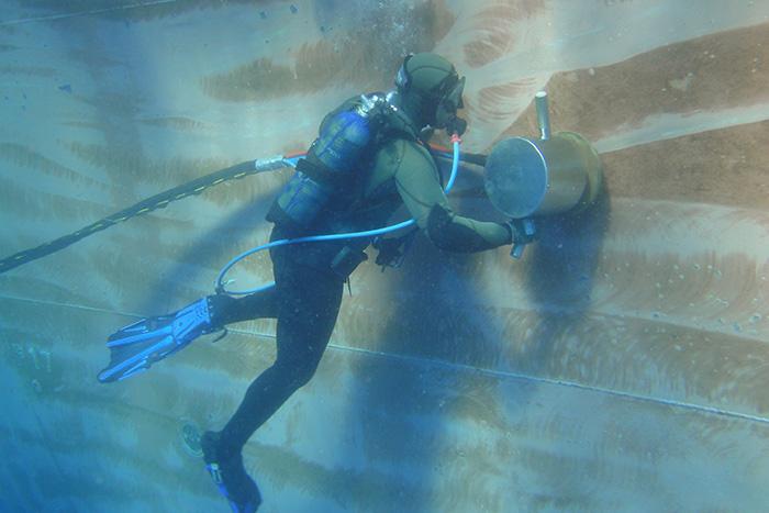 A diver cleans a ship's hull