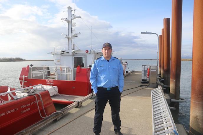 john thomas stands on a dock in front of a boat