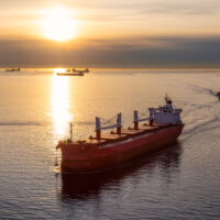 Aerial View from Above of a Cargo Ship arriving to the Port near Stanley Park during a vibrant sunny sunset.