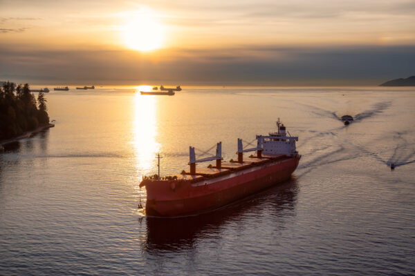 Aerial View from Above of a Cargo Ship arriving to the Port near Stanley Park during a vibrant sunny sunset.