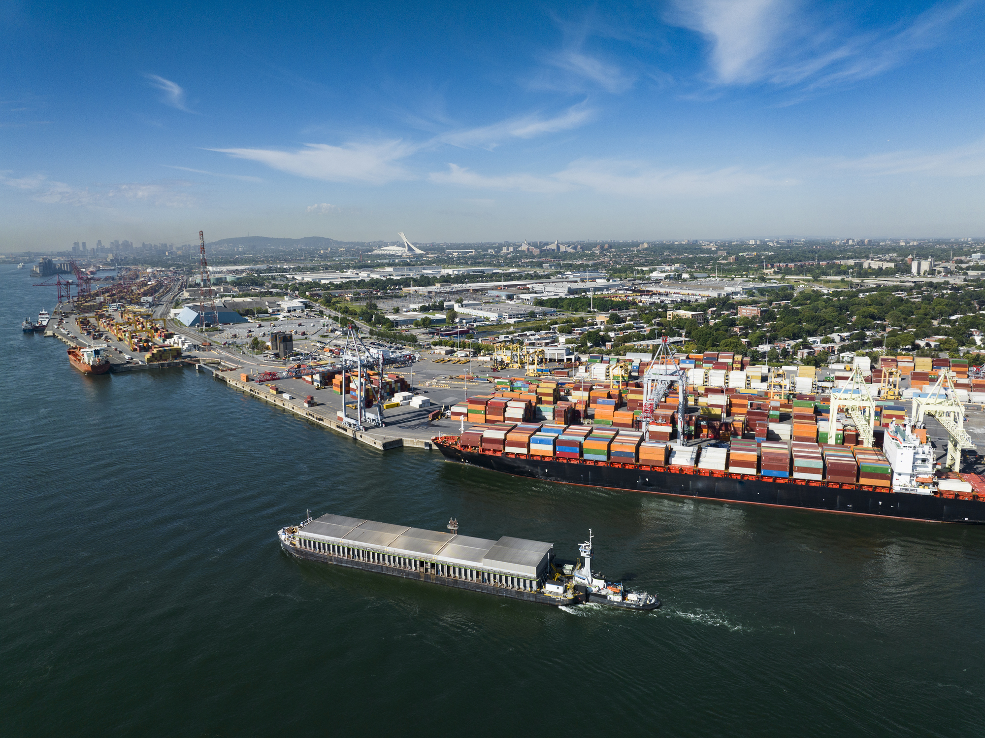 Aerial of the port of Montreal along the St. Lawrence River with the city in the background.